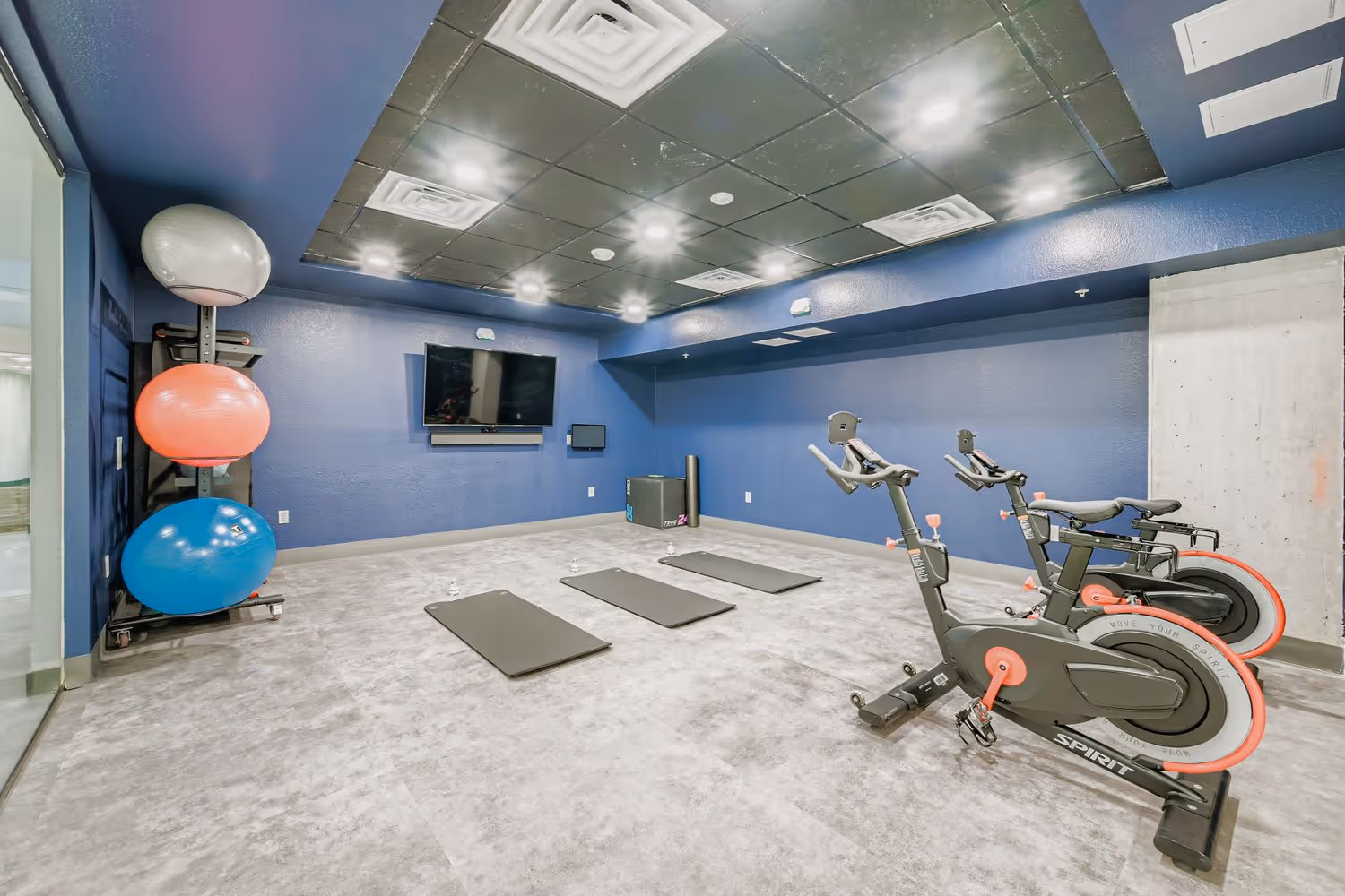 Yoga and spin studio with exercise bikes, yoga mats, and stability balls at Avian Apartments.