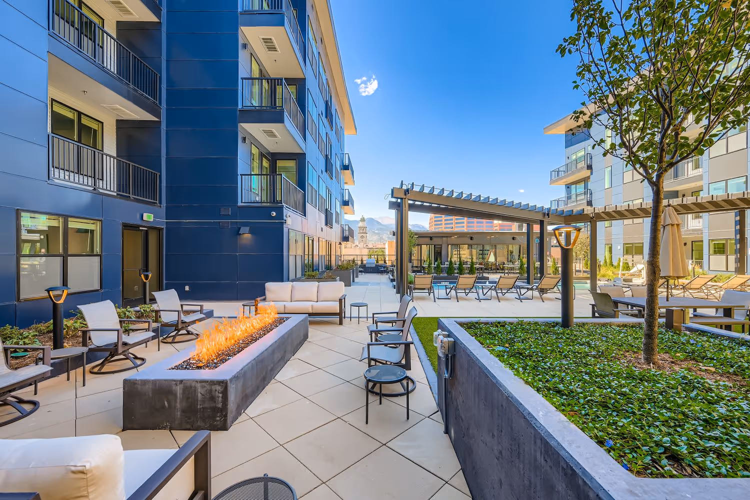 Outdoor resident fire pit lounge and barbecue area with modern seating at Avian Apartments.