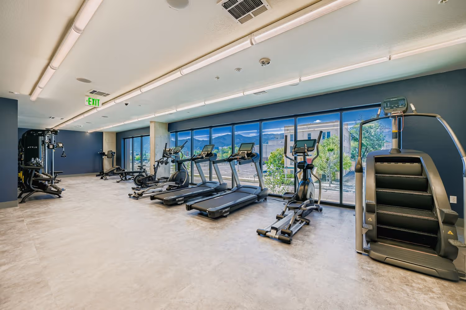 Fitness center with cardio equipment and floor-to-ceiling windows with mountain views at Avian Apartments.