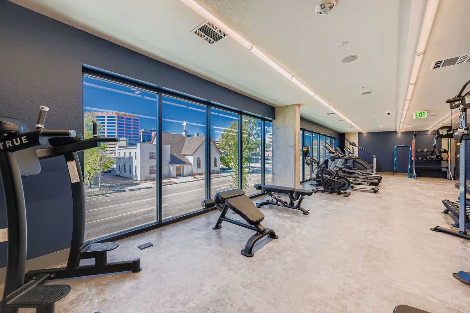 Strength training area inside the Avian Apartments fitness center with floor-to-ceiling glazing.